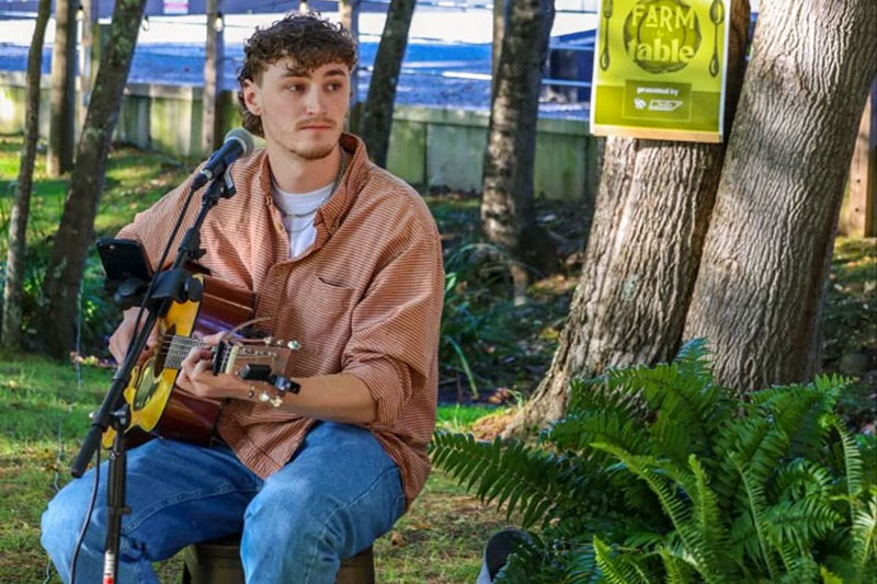 Country musician Alexander Nicoll plays guitar during an outdoor show