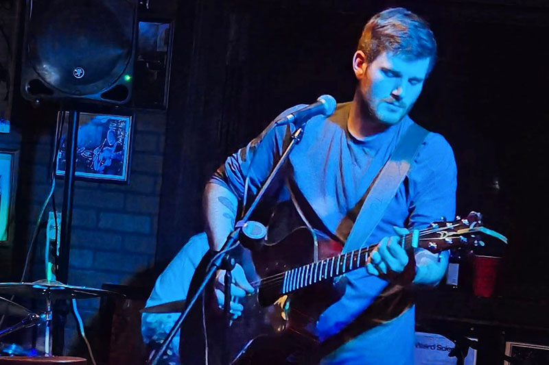 Dylan Tyler Cox playing guitar on stage