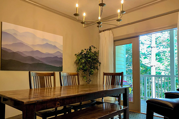 This vacation rental features a large dining room area with sliding door opening to private wooded balcony