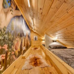 A nature mural covers the wall of this kids rooms with custom-made twin beds