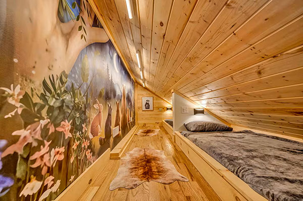 A nature mural covers the wall of this kids rooms with custom-made twin beds