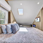 The main bedroom features a king-sized bed nestled under an A-frame ceiling with skylights.