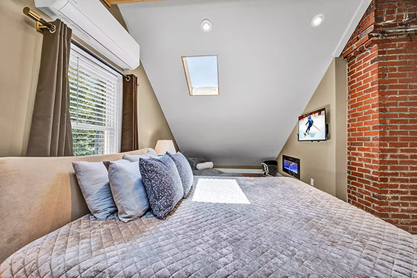 The main bedroom features a king-sized bed nestled under an A-frame ceiling with skylights.